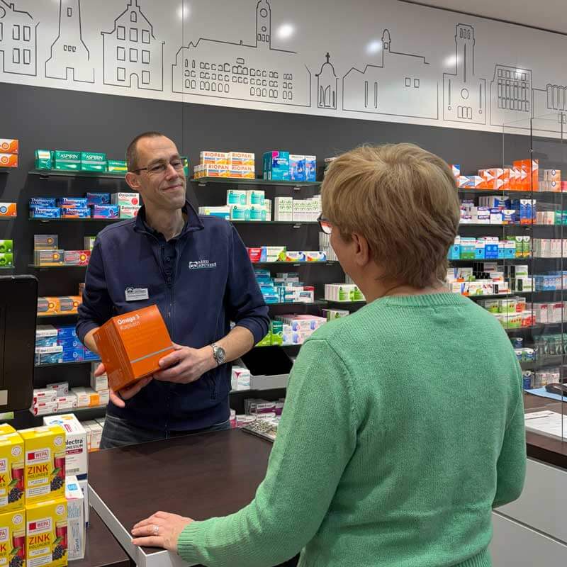 Mitarbeiter berät eine Kundin zum Thema Omega-3 Kapseln in der Bären Apotheke